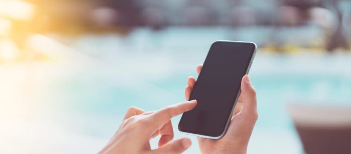 person using automation control on cell phone by pool